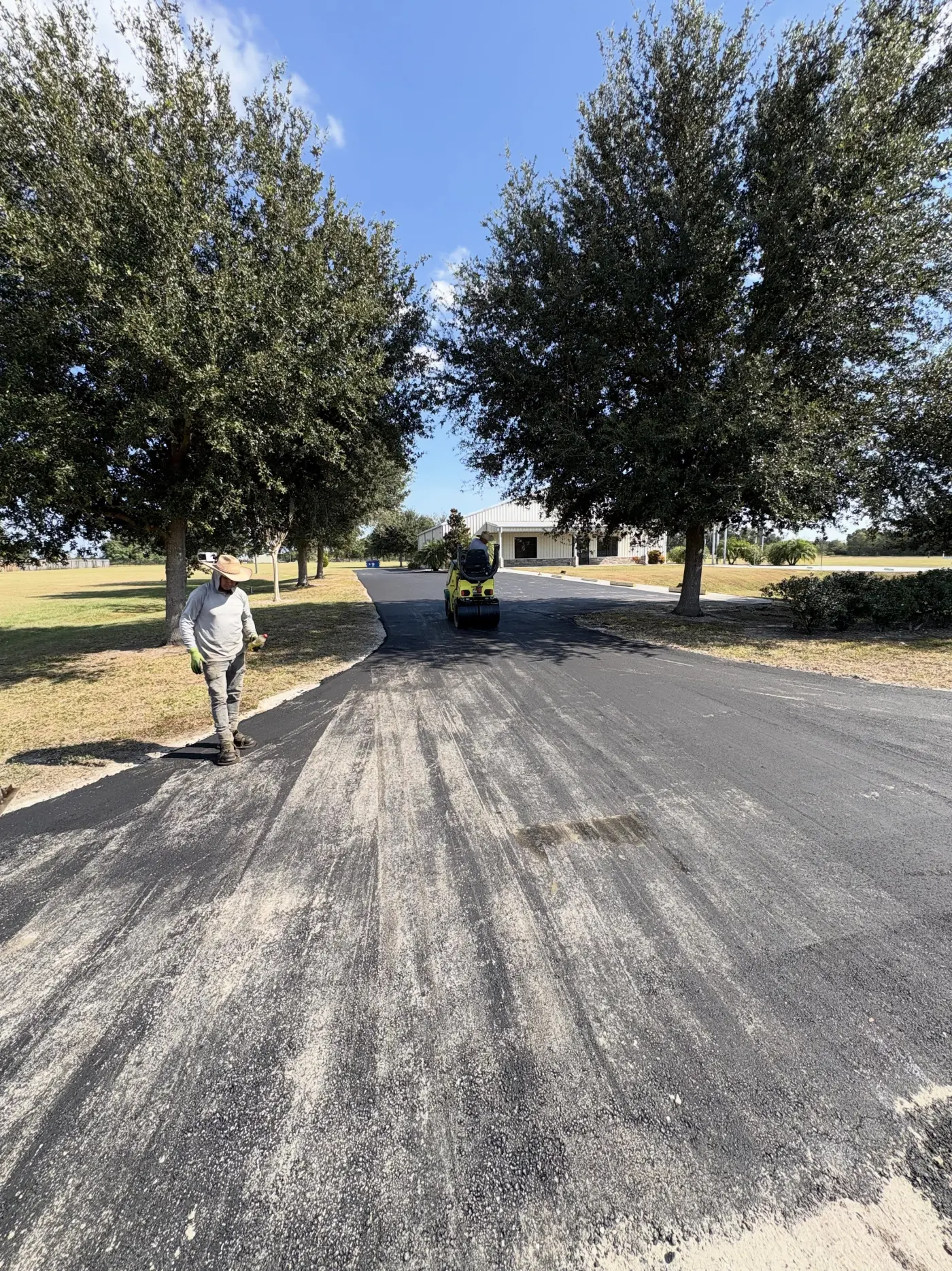 Long curving freshly paved driveway through a wooded property