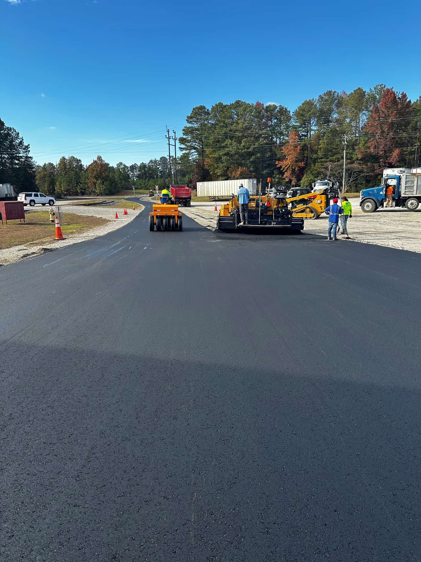 Large paver and crew laying asphalt on a commercial road